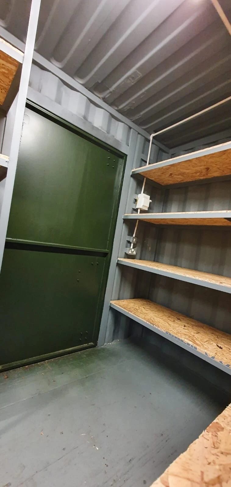 20ft High Cube Storage Container – Lighting and Shelving – Container interior with wooden shelving, electrical sockets and green door