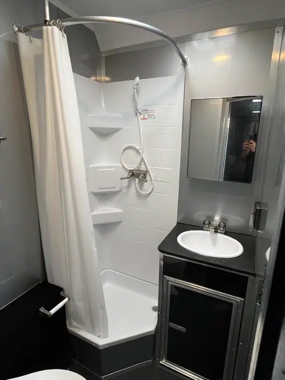 2025 Millennium 34 ft Car Trailer – Corner Bathroom – Bathroom sink vanity and mirror next to a white corner shower stall