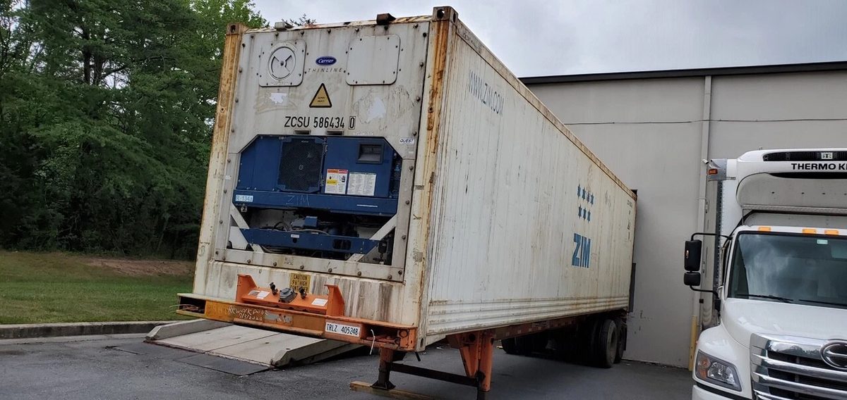 40ft High Cube Reefer Container – Non-Working, Insulated Storage – weathered refrigerated container on chassis beside a parked truck