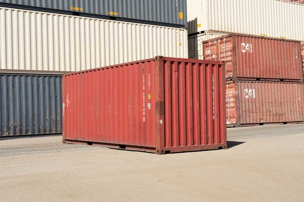 20ft Used Shipping Container – Cargo-Worthy, Standard Height – three-quarter exterior of weathered red container in storage yard