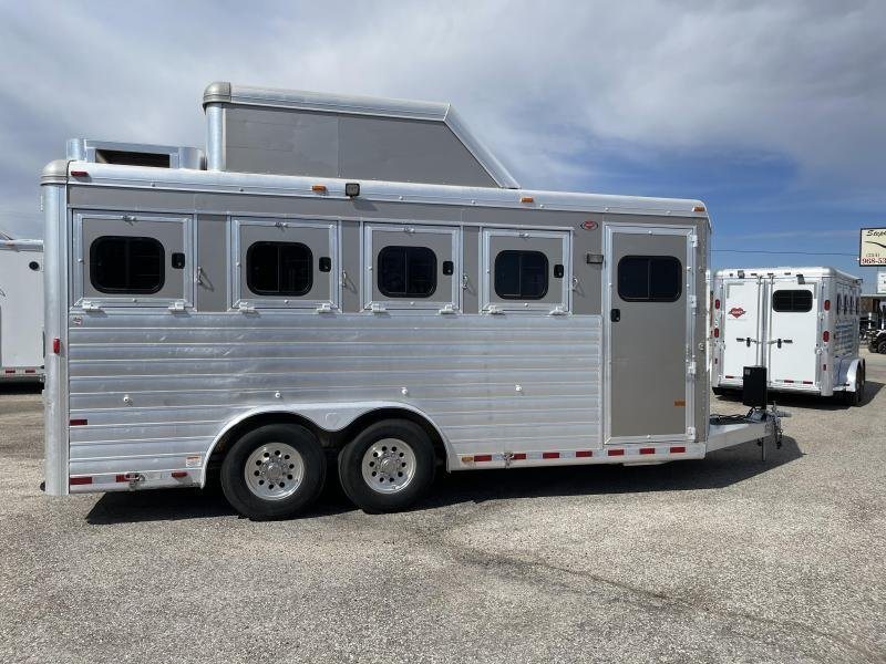 2016 Hart Ultimate 4 Horse Trailer – Champagne, Hay Pod – A flat side view of the trailer featuring multiple stall windows and axles