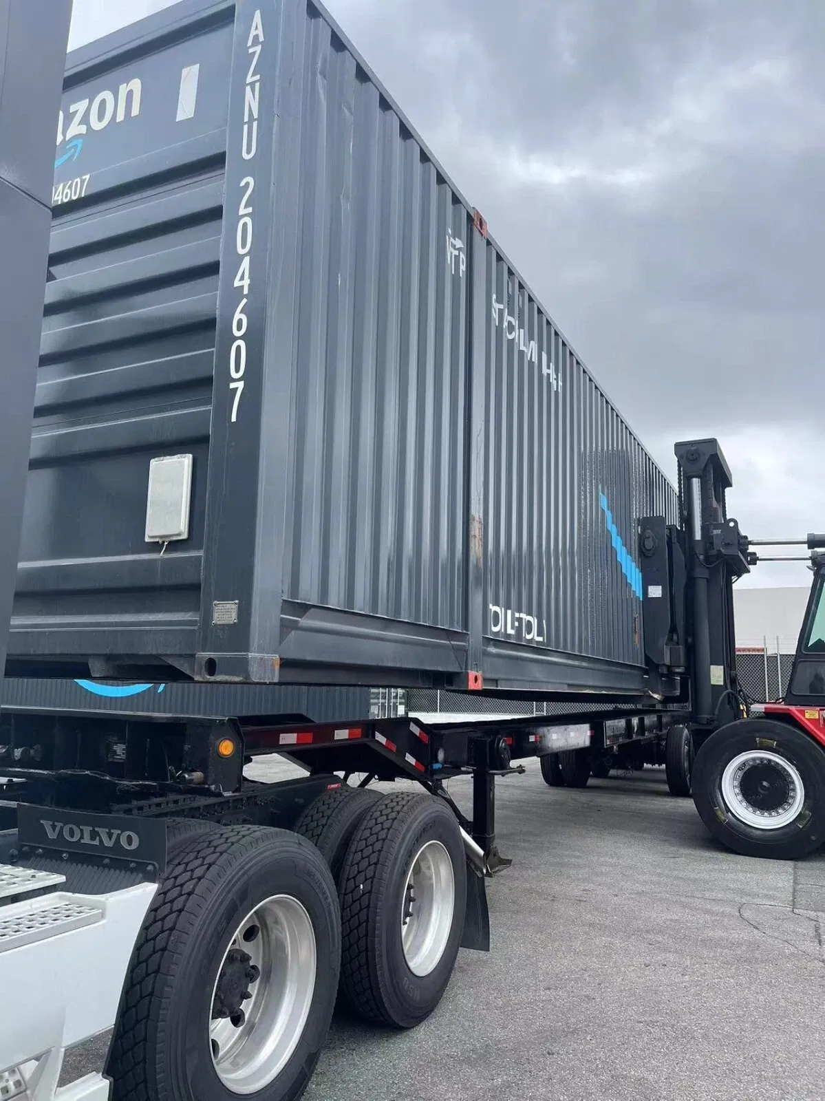 53ft High Cube Shipping Container – Used, Multi-Trip – dark gray shipping container being loaded onto a trailer