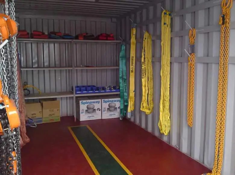 Trade Show Display Container – Lockable Steel Booth – Interior of a shipping container with metal shelving and hanging lifting equipment