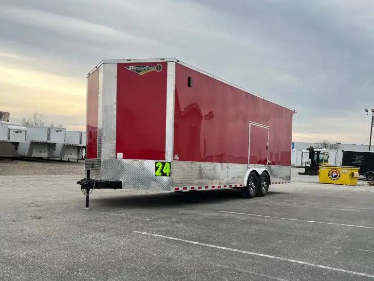 2026 Millennium 24 ft Car Hauler – Red, Econo-Max – Front three-quarter view showing the hitch and side of the red enclosed car hauler