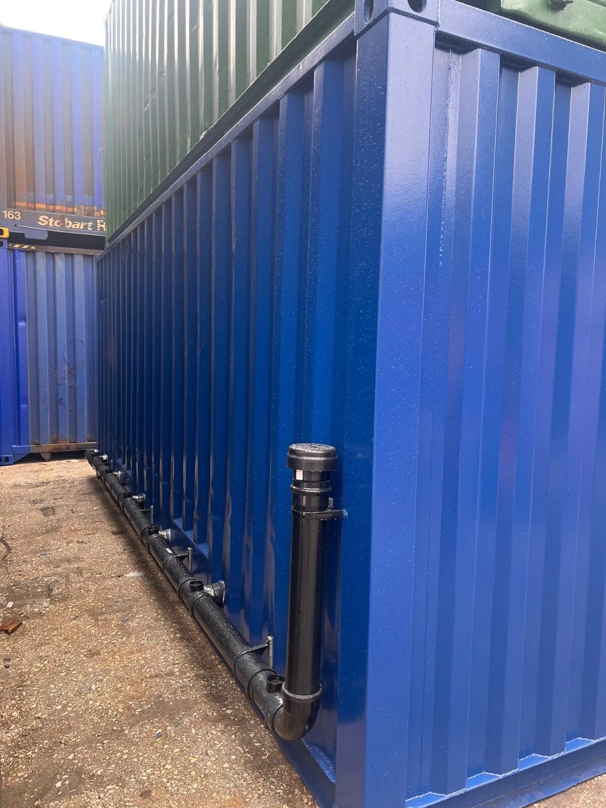 20ft Refurbished Container Toilet Block – Separate Compartments – blue container exterior with exposed black drainage pipes