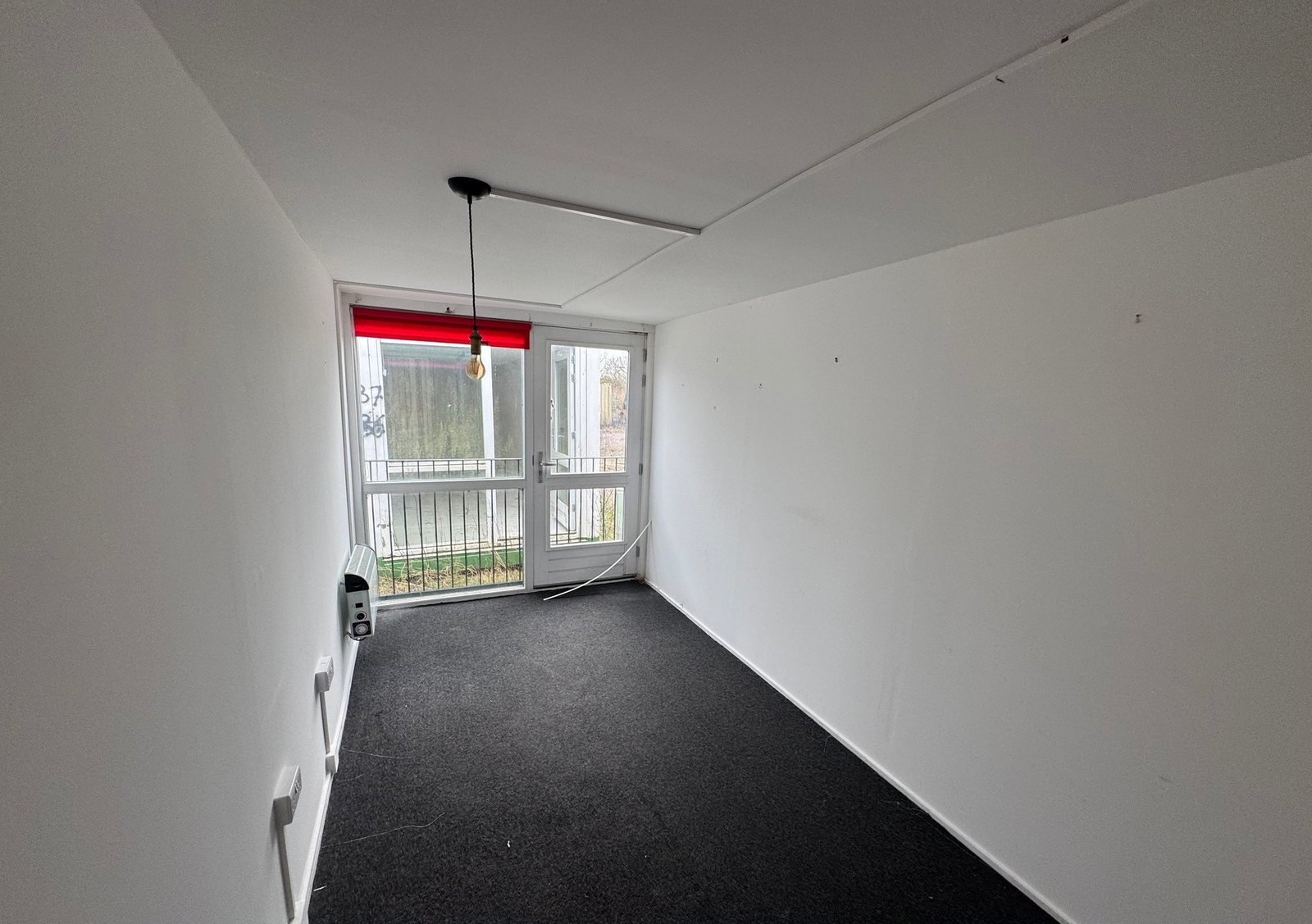 40ft Container Home – Two-Room Conversion – Inside view of an unrefurbished 40ft container room showing the white finished walls and black flooring with natural light