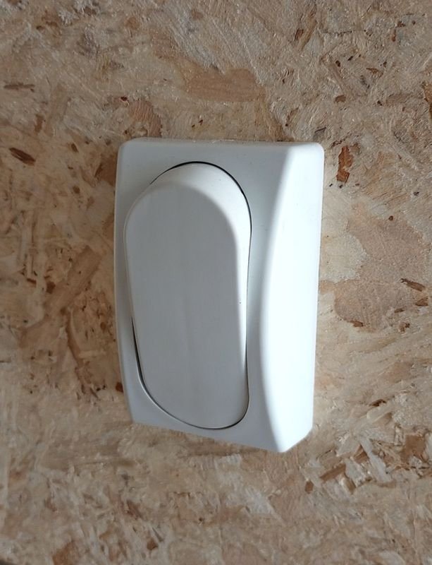 Mission Trailers 22 ft Snowmobile Trailer – 4-Place – A white plastic light switch mounted on a wood-textured interior wall panel
