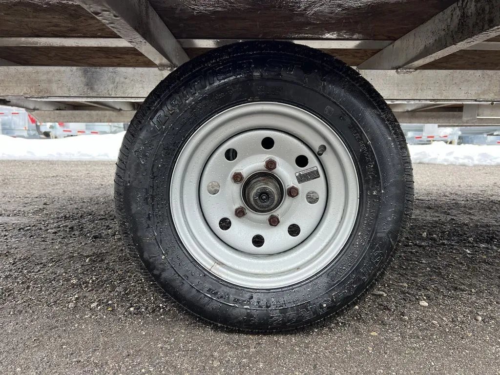 2022 High Country 12 ft Hybrid Trailer – Track Mats – Close-up of a single trailer tire and white steel wheel assembly