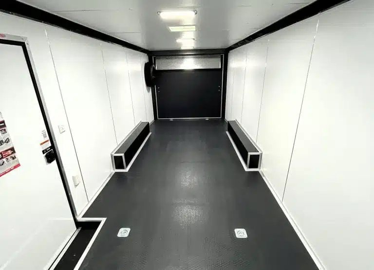 2025 Millennium 24 ft Car Hauler – Charcoal – Finished white interior looking towards the rear ramp door with black flooring