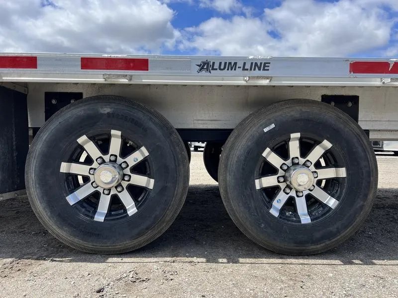 2024 Alum-Line 24 ft Gooseneck – Flip-Over Ramps – Close-up view of the dual axles and black custom wheels with silver accents