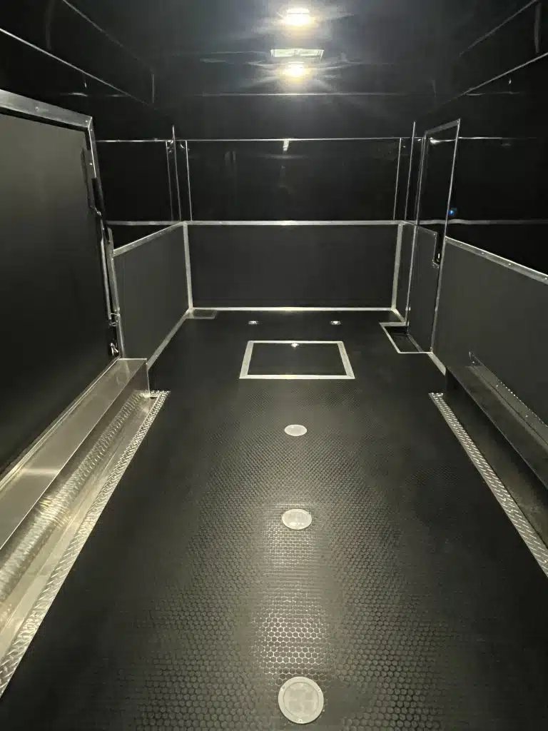 2026 Haulmark 20 ft Car Trailer – Large Escape Door – View of the black finished interior floor and walls with ceiling lights