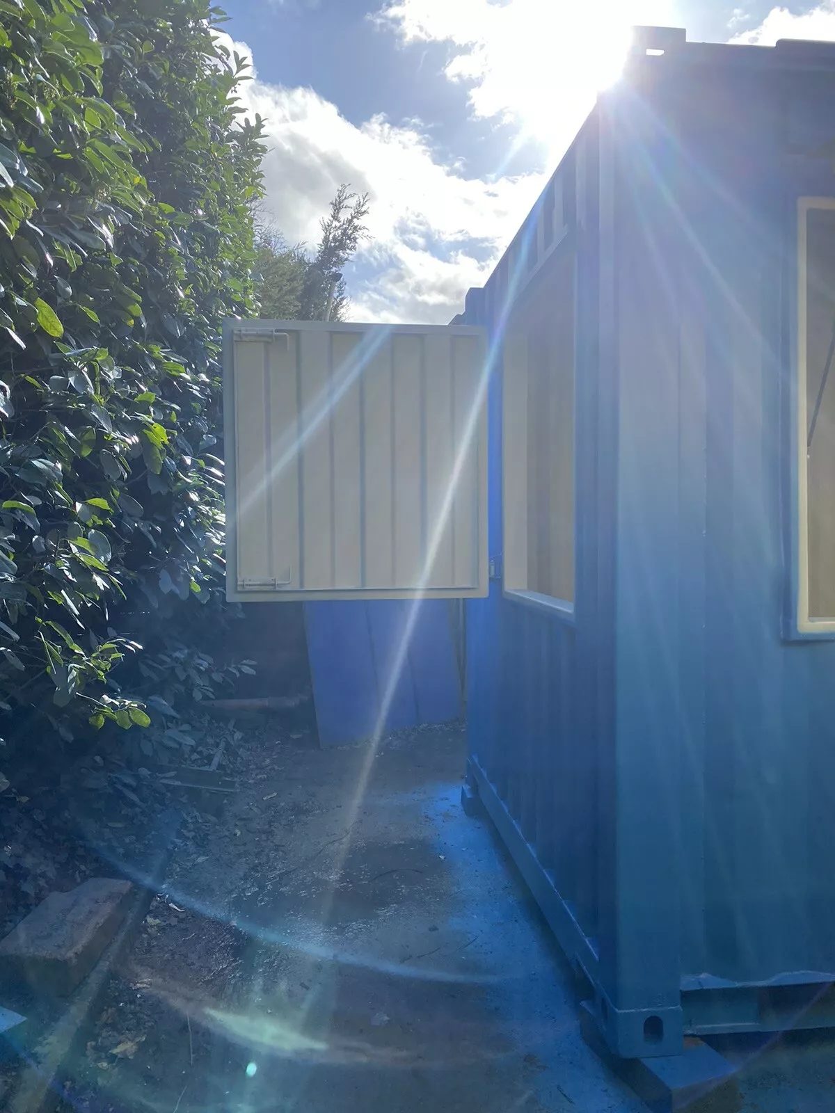 15ft Custom Container Bar & Kiosk – Side Service Hatches – blue converted container with open side hatch beside hedge