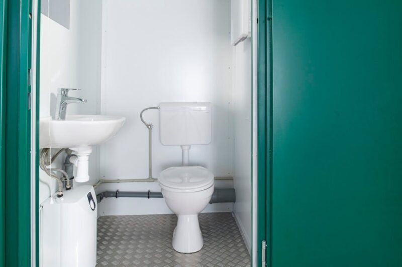 Double Mains Toilet – Green, Two Toilets – View through the doorway showing the complete bathroom layout with toilet and sink