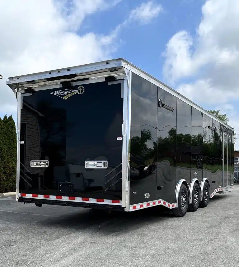 2025 Haulmark Edge 34 ft Race Trailer – Turbo Package – Rear three-quarter view of a black enclosed trailer with triple axles and chrome trim