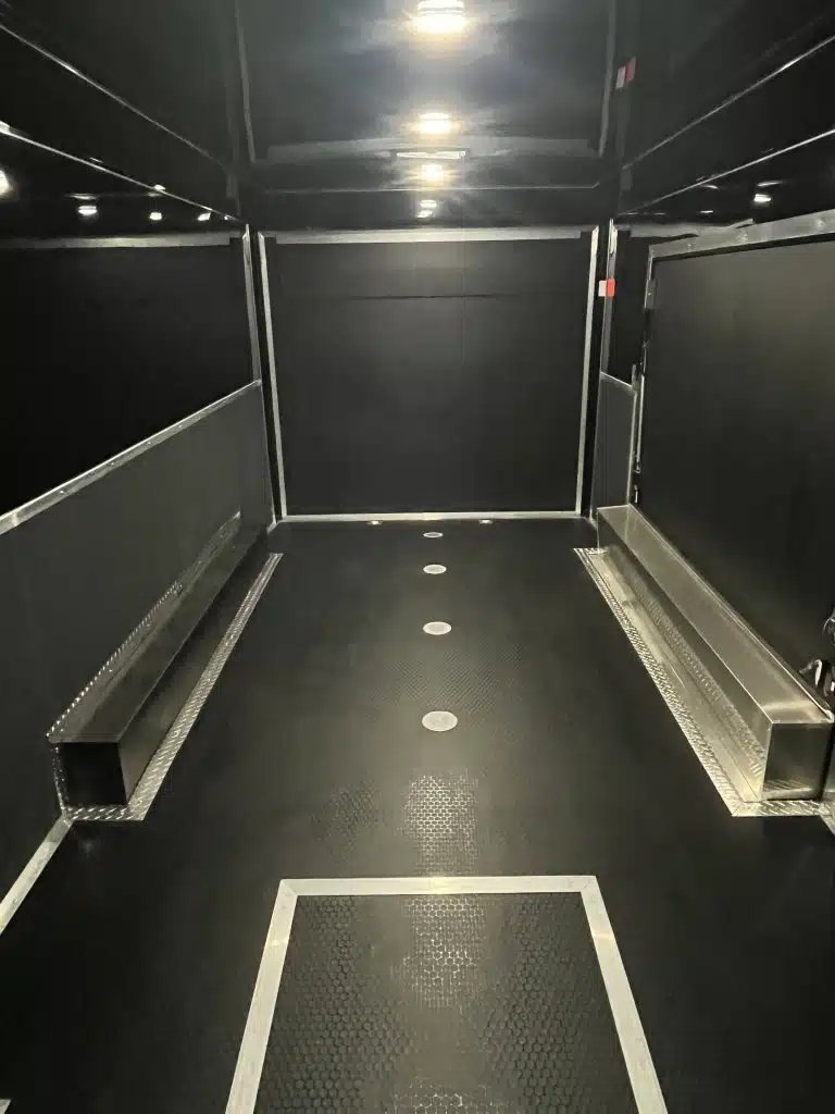 2026 Haulmark 20 ft Car Trailer – Large Escape Door – Interior shot showing black walls, overhead lighting, and wheel well covers