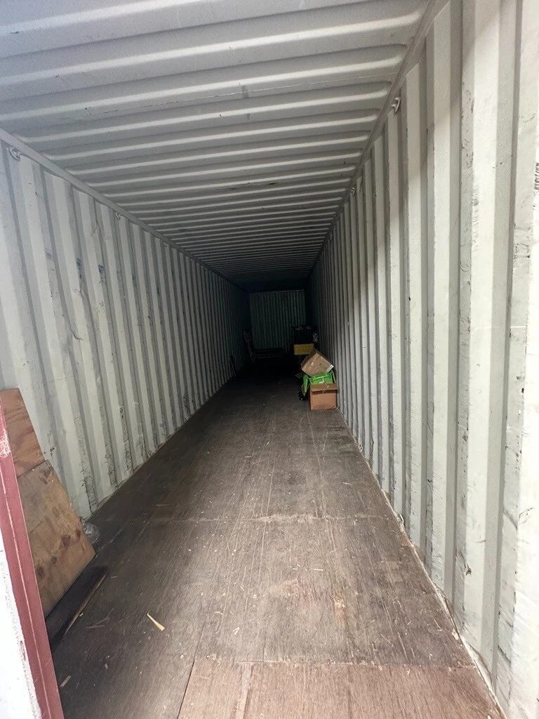 40ft High Cube Shipping Container – Used, Double Rear Doors – Mostly empty container interior with wooden floor and scattered boxes