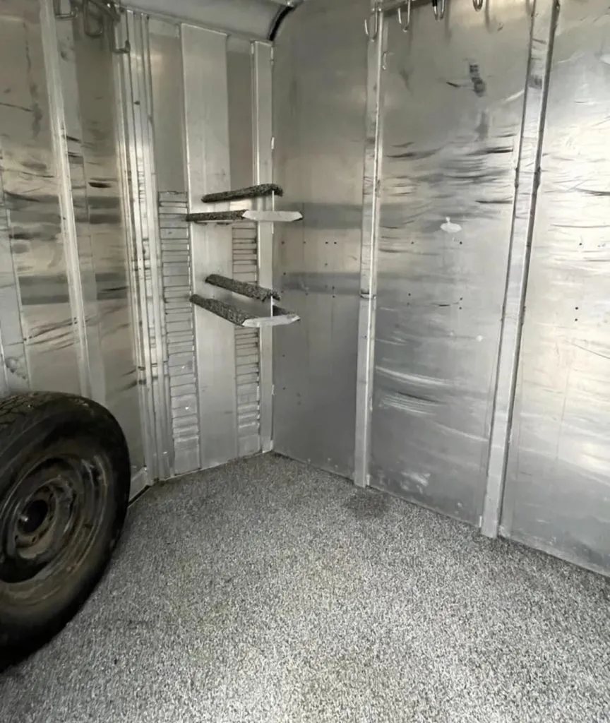 1999 4 Star 2 Horse Trailer – Reverse Slant / Stock Combo – Inside view of the tack room area showing saddle racks and spare tire