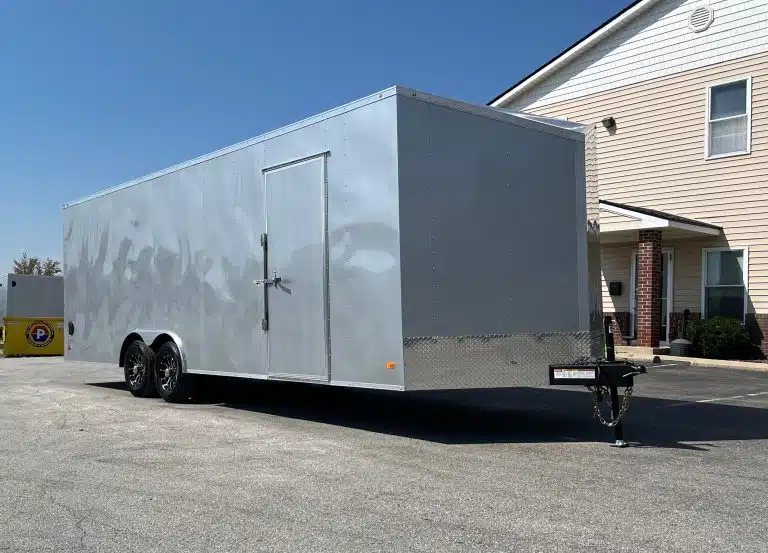 2026 Millennium 24 ft Car Hauler – Silver Hero – Passenger side of a silver enclosed trailer showing the side entry door and black wheels