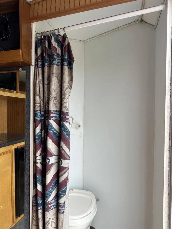 2004 Hart 3 Horse Gooseneck Trailer – Weekender Living Quarters – A small bathroom area with a toilet and a patterned shower curtain