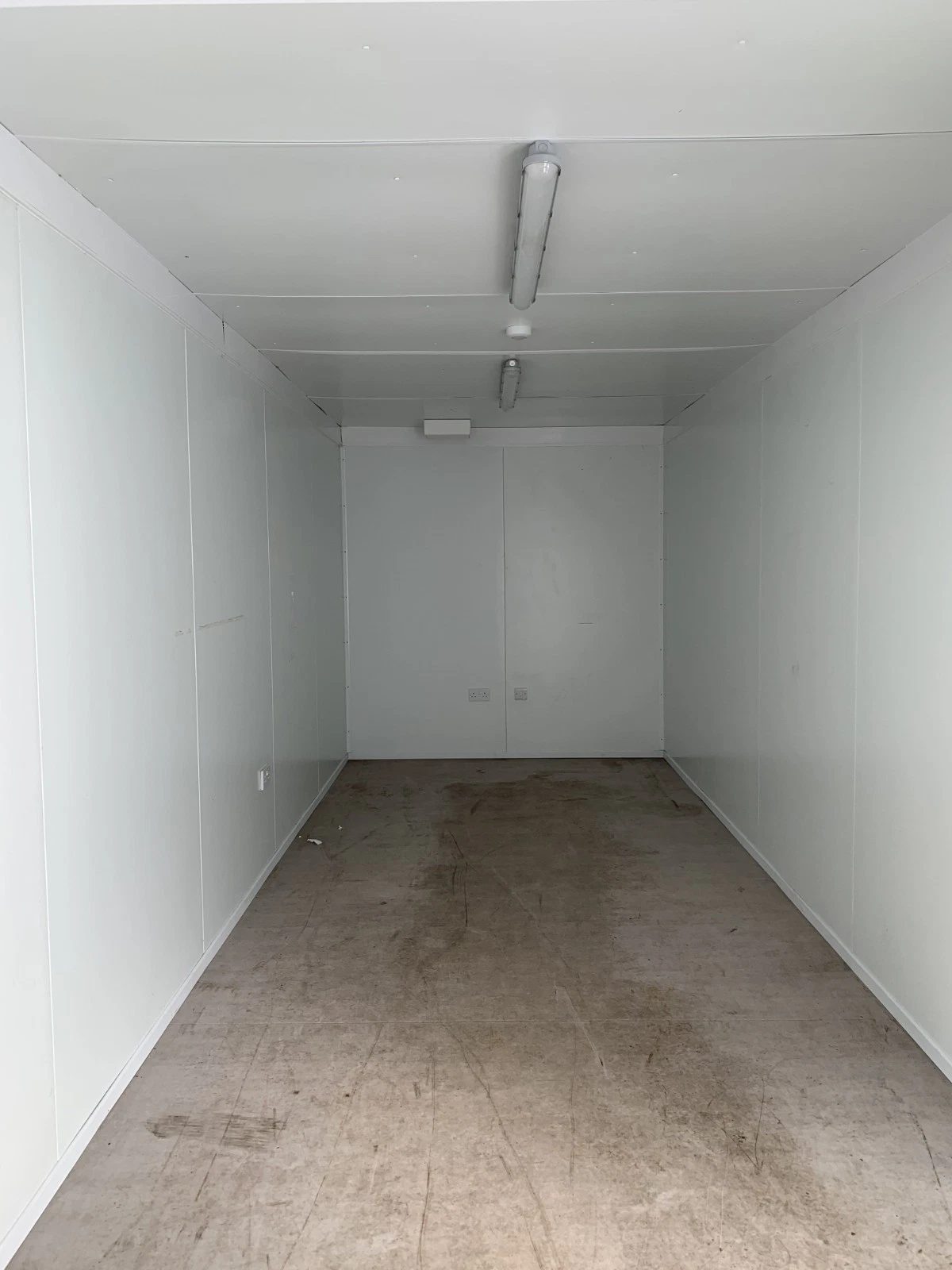 20ft Insulated Storage Container – Lockable Double Doors – empty insulated interior with white panels and worn flooring