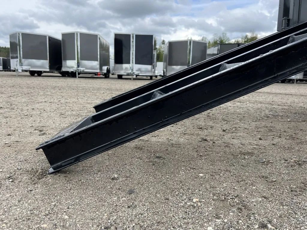 2024 RawMaxx 10 ft Dump Trailer – Shadow Grey – Close-up of a black metal loading ramp resting on the gravel ground