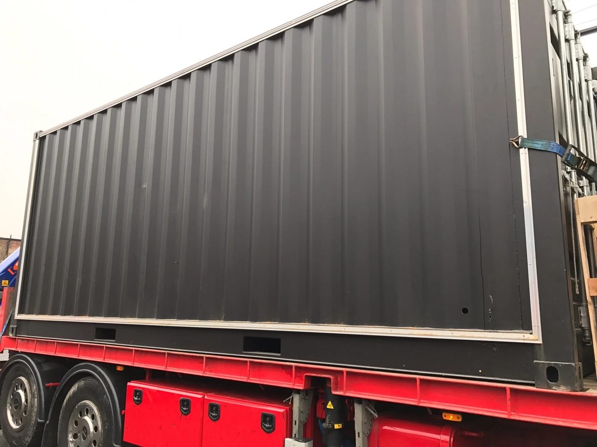 20ft Used Shipping Container – Integrated Glass Windows – dark gray container side on a red transport truck