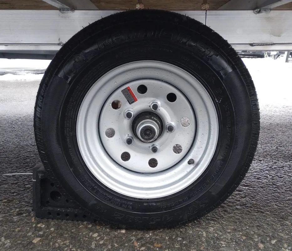 2024 Mission Trailers 12 ft Powersports – Side X Side – Close up view of the black tire and silver rim of the trailer