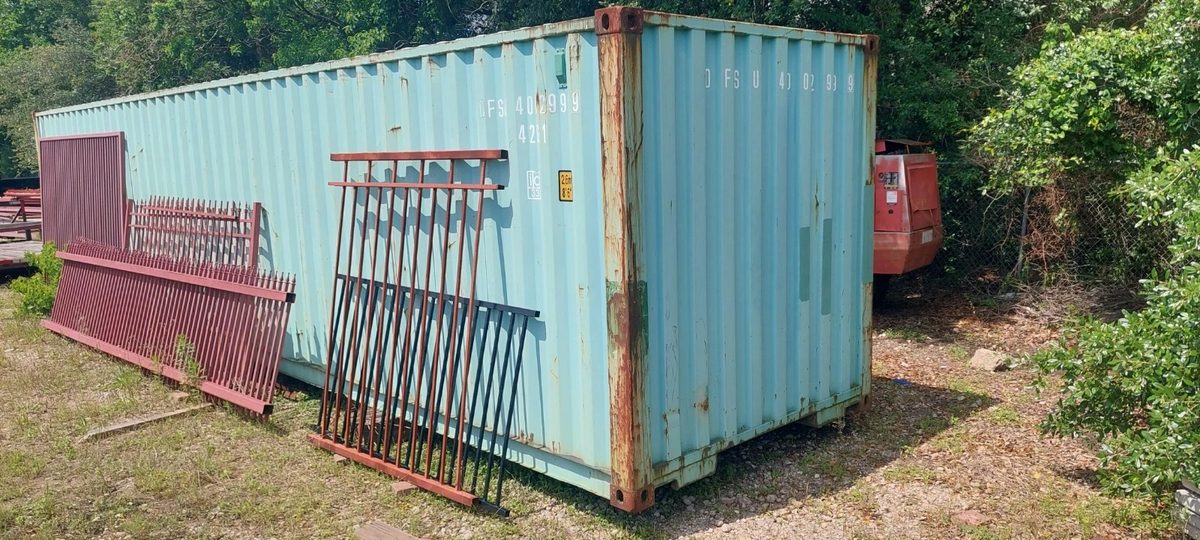 40ft Used Shipping Container – Wind & Watertight Storage – weathered shipping container with metal fence panels leaning against side