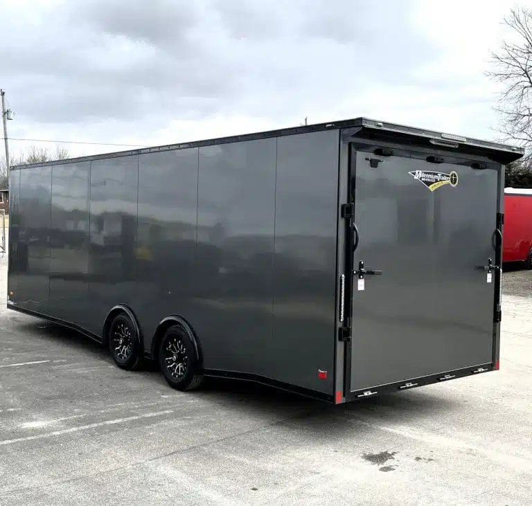 2025 Millennium 24 ft Car Hauler – Charcoal – Rear perspective of the grey enclosed trailer showing the rear ramp and dual axles