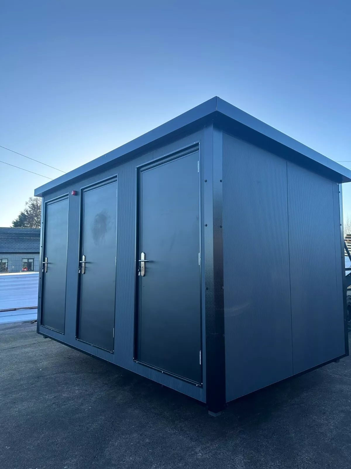 Custom Shipping Container Restroom – Three Private Compartments – Three-quarter exterior view of restroom unit with three closed doors