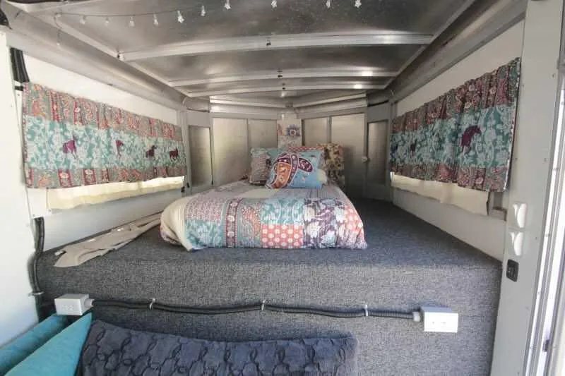 1999 Sundowner 20 ft Horse Trailer – Weekender – Sleeping area in the gooseneck with a bed, pillows, and curtains