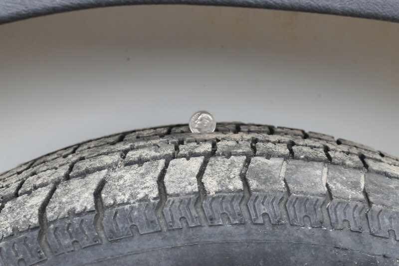2005 Sundowner 2 Horse Trailer – Sunlite Straight Load – Close up of tire tread depth being measured with a coin