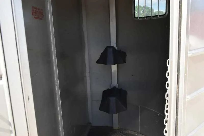 2010 Calico 2 Horse Trailer – Steel, Walk-In Dressing Room – Interior of the front tack room featuring two black saddle racks on a post