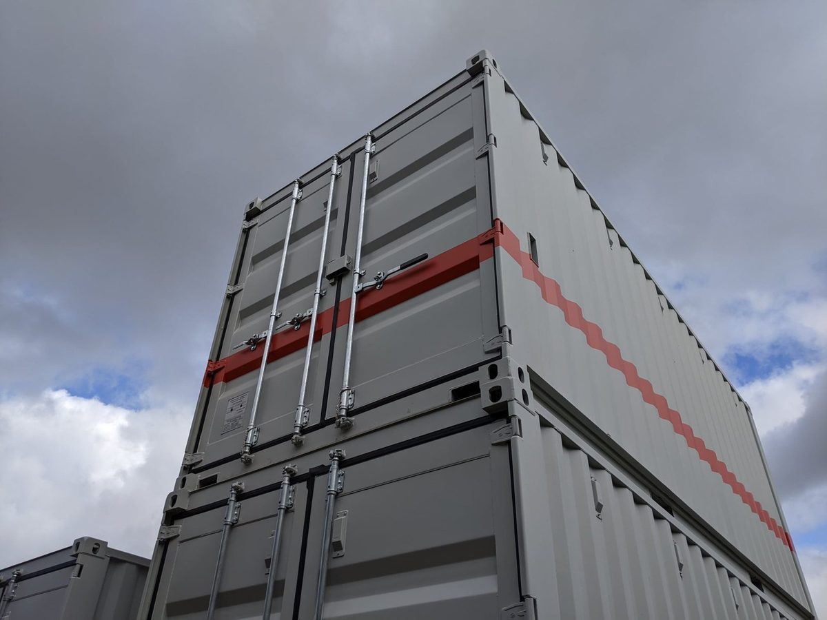 20ft Custom Workshop Container – Built-In Steel Shelving – low-angle view of stacked containers with closed cargo doors