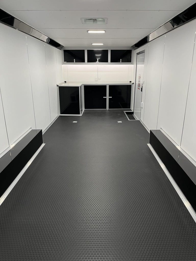 2026 Millennium Extreme 28 ft Enclosed Car Hauler – White – Interior view of trailer showing black cabinets and workbench at the front