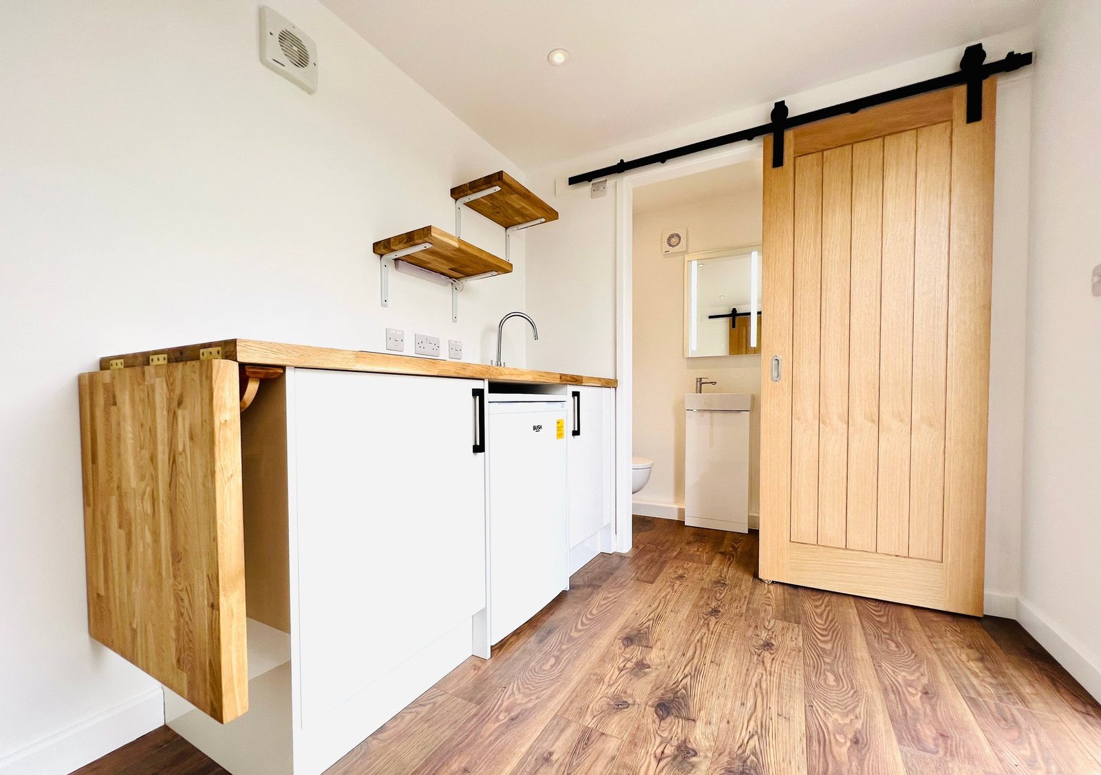 20ft Container Home – One Bed Box, 1 Bedroom – A modern 20ft shipping container conversion featuring a compact kitchenette, wood finishes, and space-saving sliding door
