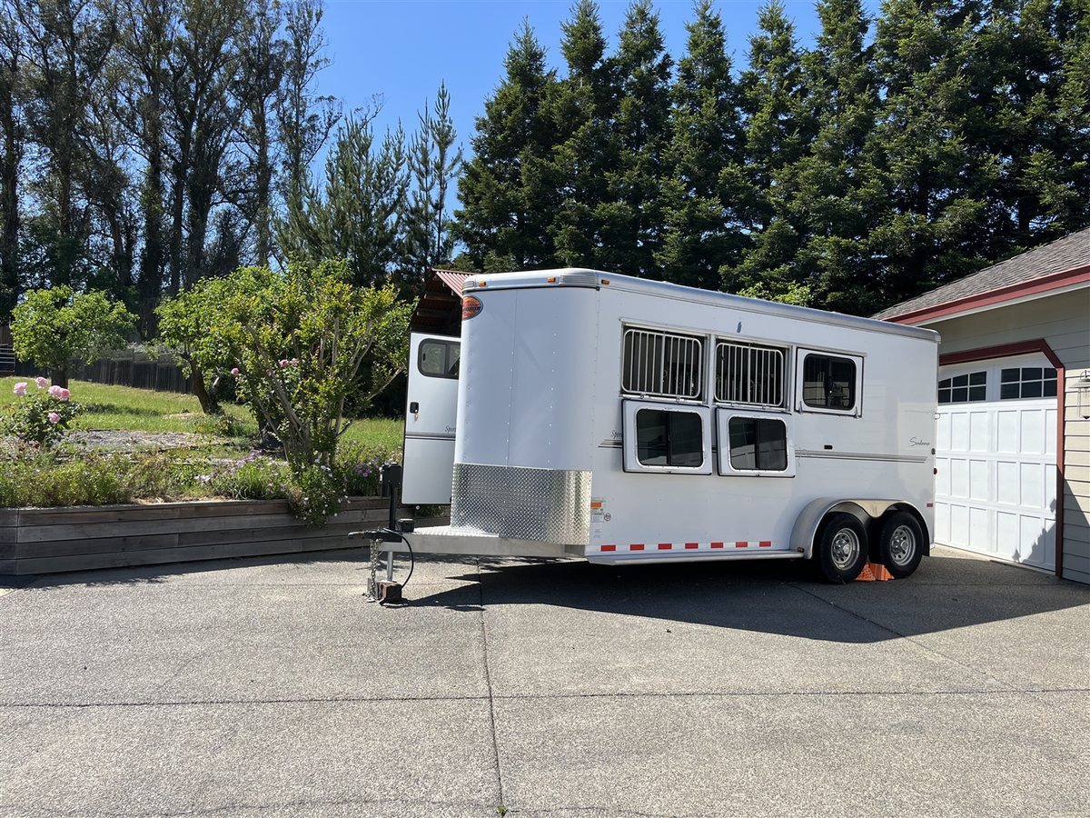 2013 Sundowner Sportsman 3 Horse Trailer – Extra-Large Tack Room – A three-quarter exterior view of a white three horse trailer parked on a driveway