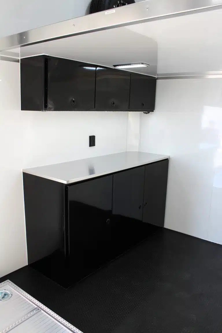2026 ATC 26 ft Stacker Trailer – Tiltable Lift – Black lower and upper storage cabinets with a silver workbench inside the trailer