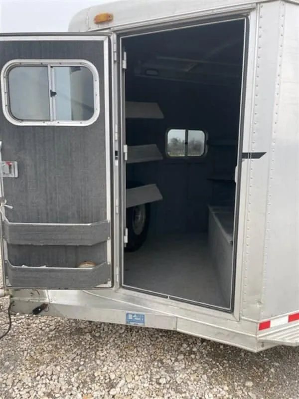 1999 Elite Custom 3 Horse Trailer – Rotating Saddle Rack – Open tack room door showing the interior storage space and shelves