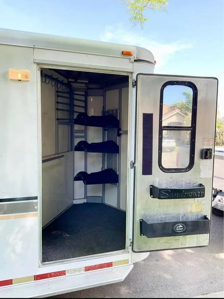 1999 Sundowner 3 Horse Trailer – Removable Rear Tack – Open tack room door revealing saddle racks and bridle hooks inside storage
