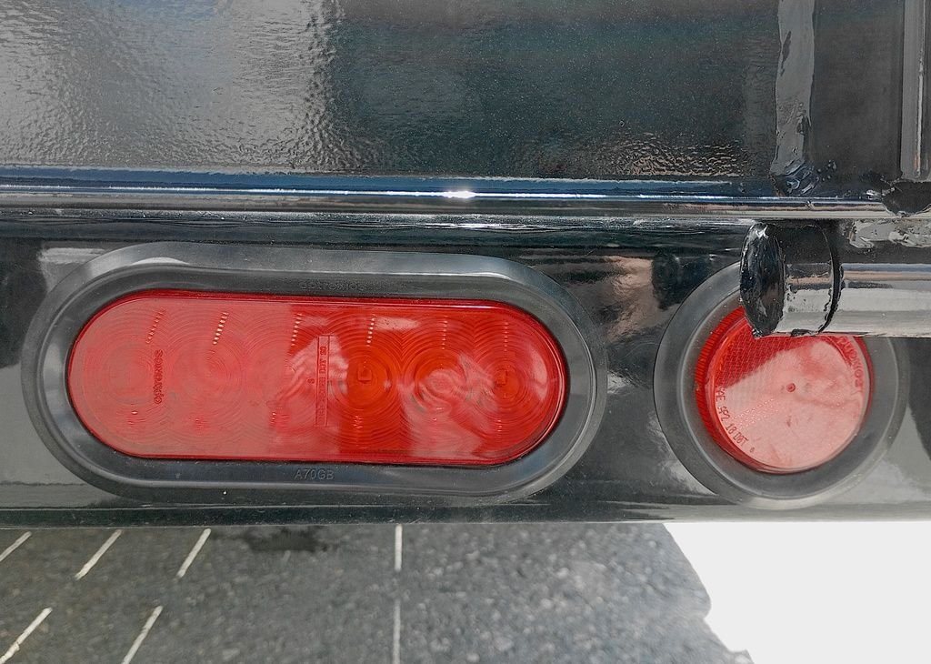 2024 PJ Trailers 14 ft Utility – Solid Metal Sides – Close-up of the red oval LED tail light and circular side marker light