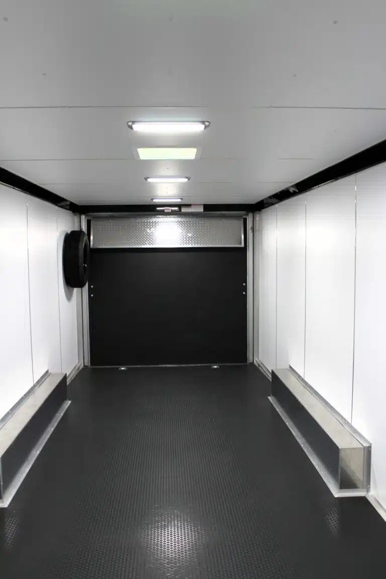 2026 Millennium 24 ft Car Hauler – White Blaze – Interior view of the trailer with black floors and white walls facing the rear