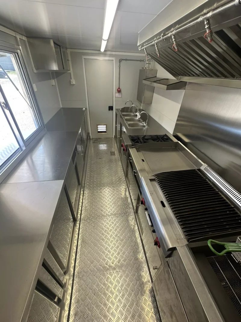 14 ft Food Trailer – Red Finish – Aisle view showing the grill, fryer, sink, and prep areas