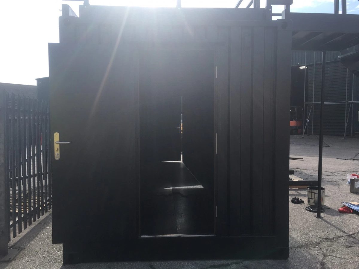 20ft Converted Shipping Container – Serving Hatches and Roof Deck – open personnel door on dark converted shipping container