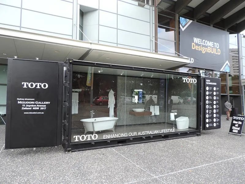 Trade Show Display Container – Lockable Steel Booth – Black shipping container modified with large glass display windows showing bathroom fixtures