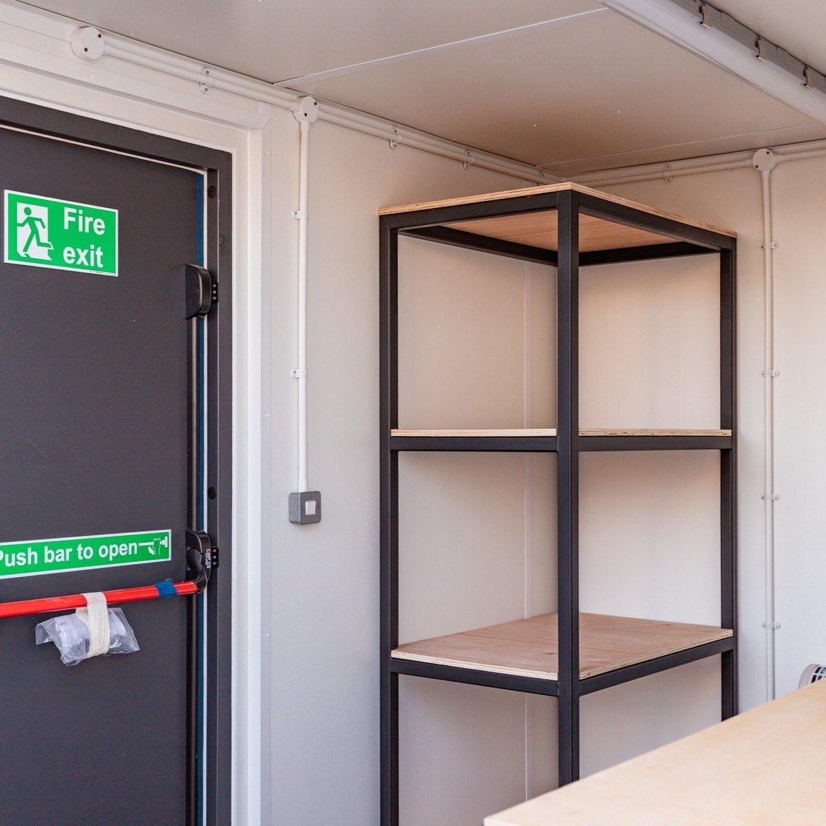 10ft Custom Workshop Shipping Container – Unfitted Steel Shell – workshop interior with storage shelving and emergency exit door