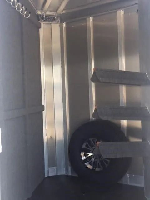 2018 Platinum Coach 3 Horse Bumper Pull – Rear Tack – View of the spare tire and saddle rack tiers inside the tack room