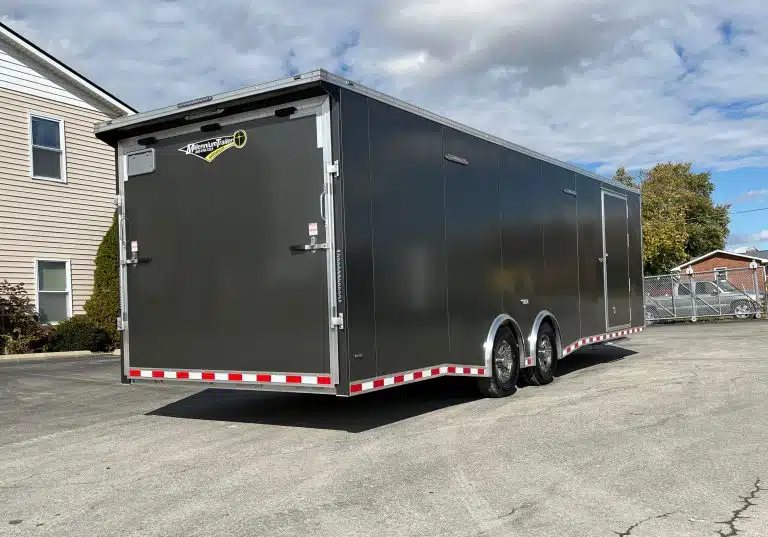2026 Millennium 28 ft Aluminum Car Hauler – Extreme – A rear three-quarter view of a grey enclosed trailer showing the ramp door closed
