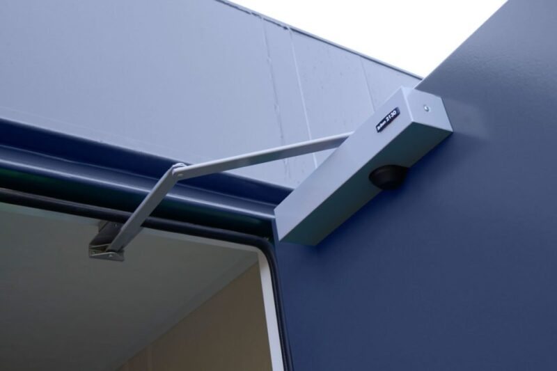 32 ft ECOlink Meeting Room Cabin – Blue – Close-up view of a hydraulic door closer mounted on the upper frame of a blue door