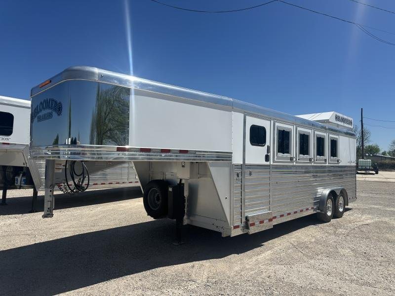 2020 Bloomer 4 Horse Stock Combo – Trainer Tack – Front three-quarter view of a white and silver gooseneck horse trailer on gravel